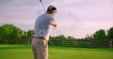 年轻英俊的高尔夫球手，日落时在美丽的球场上<strong>挥杆</strong>击球。